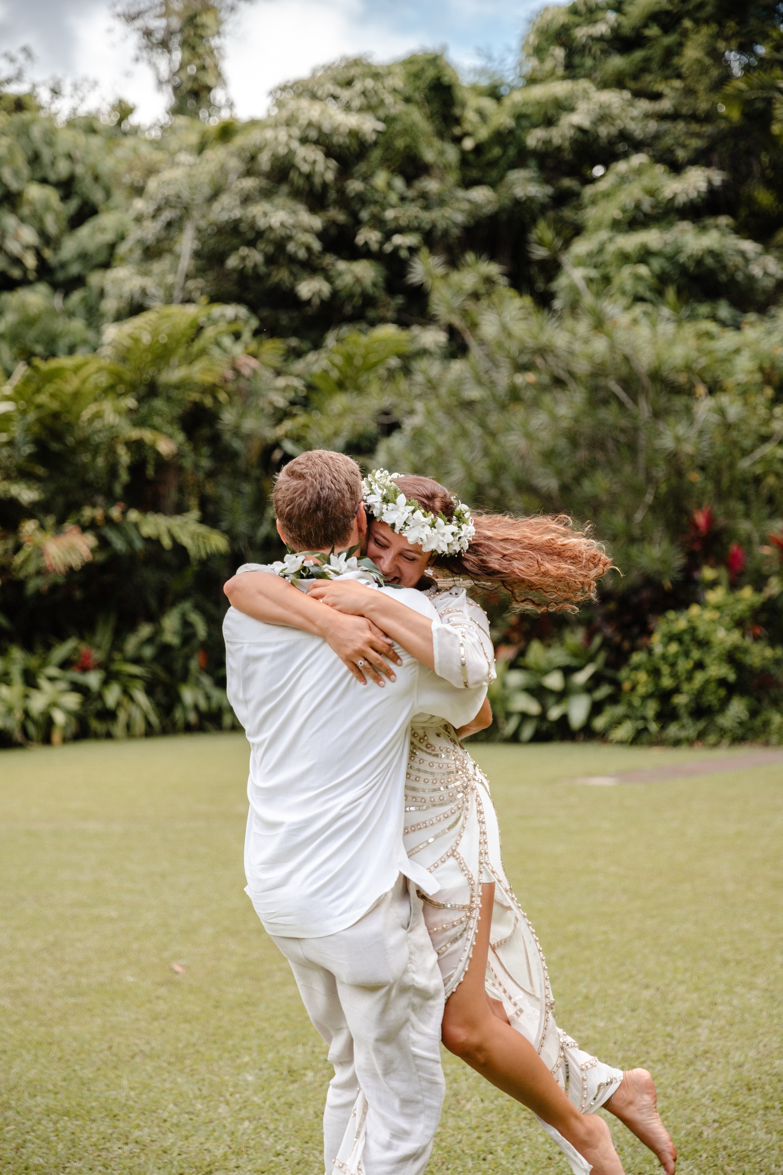 A groom lifting the bride in a spinning hug on the lawn