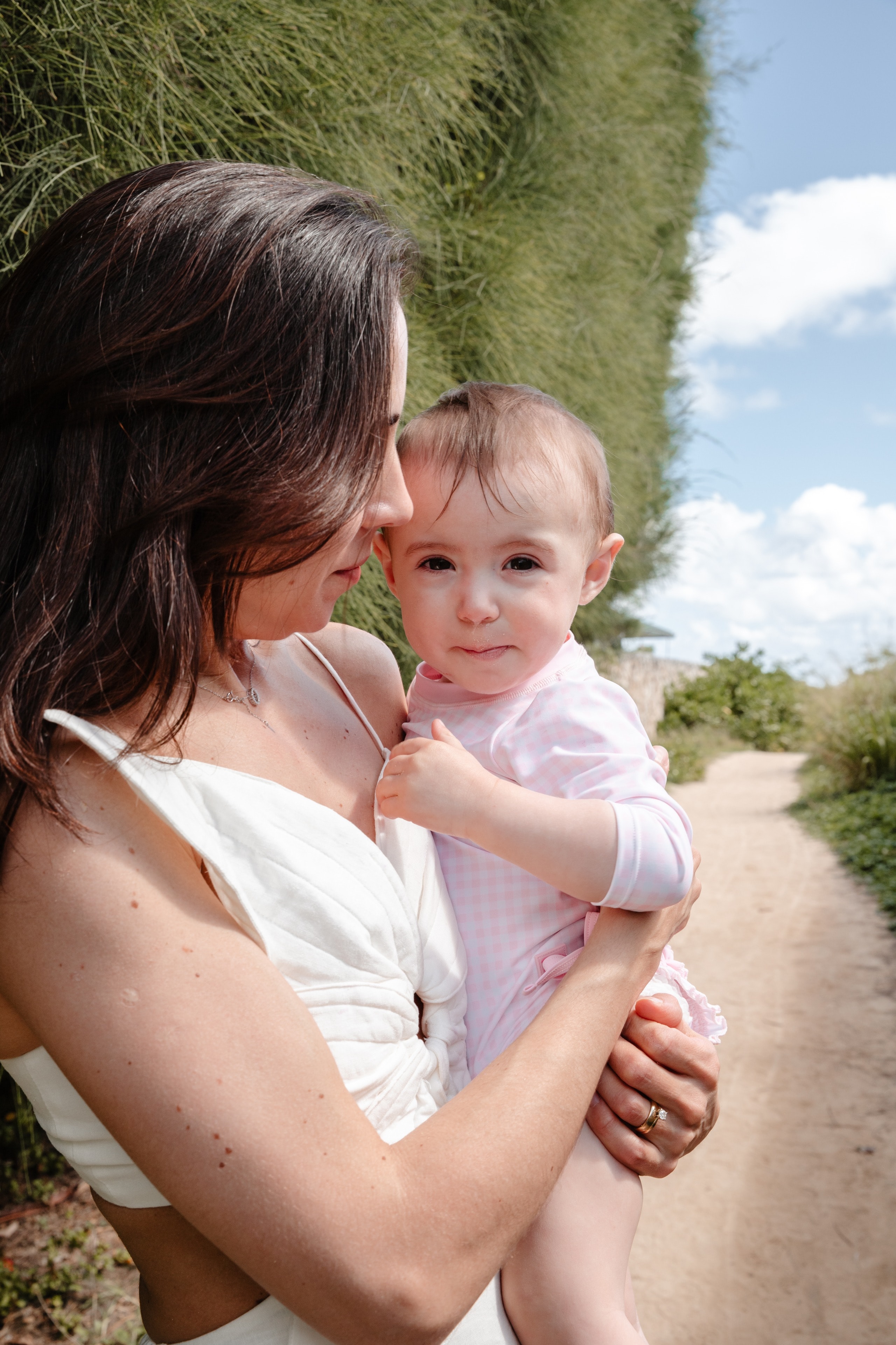 A mother holding her baby on a sandy path