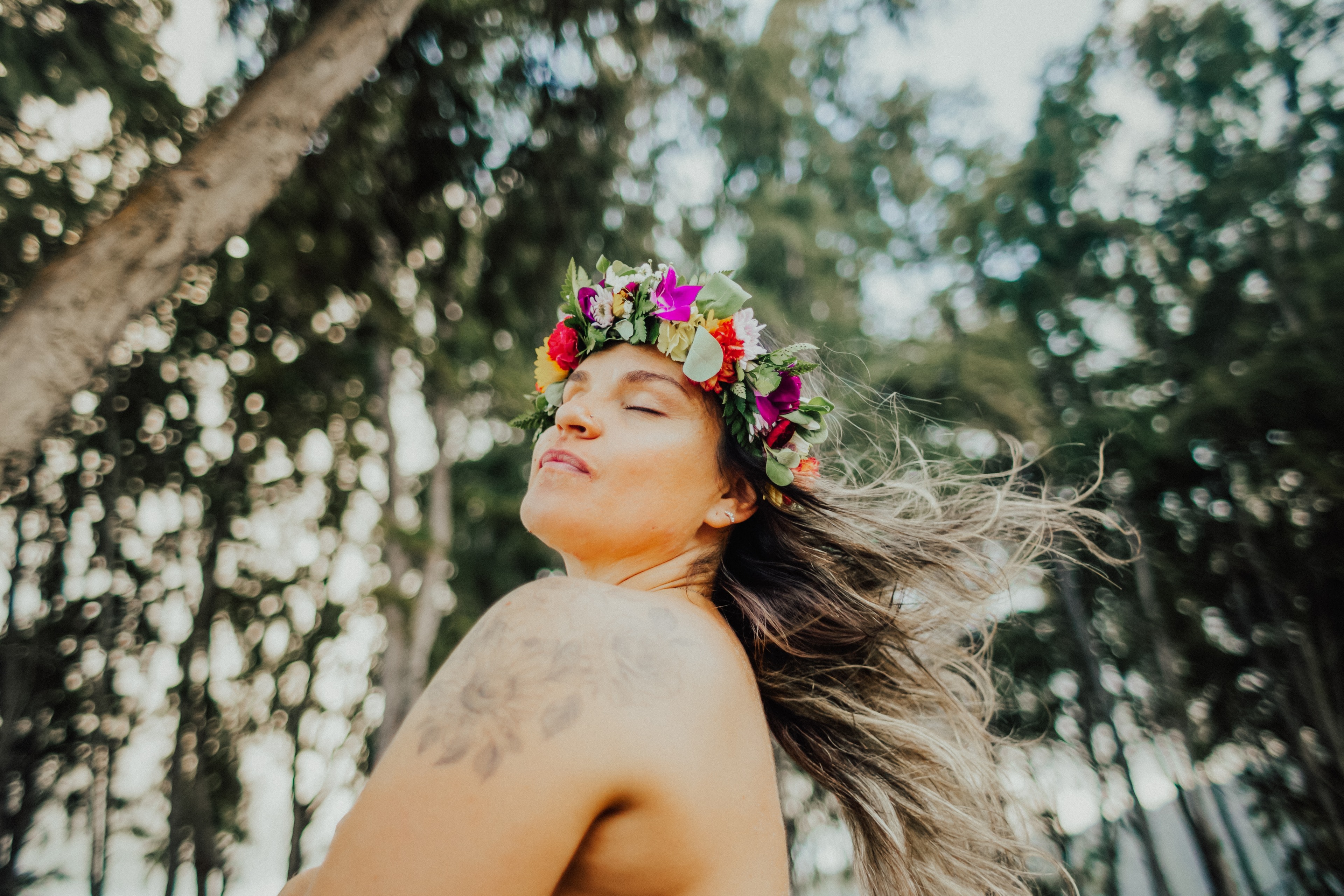 A woman with a flower crown, eyes closed, hair moving in the wind